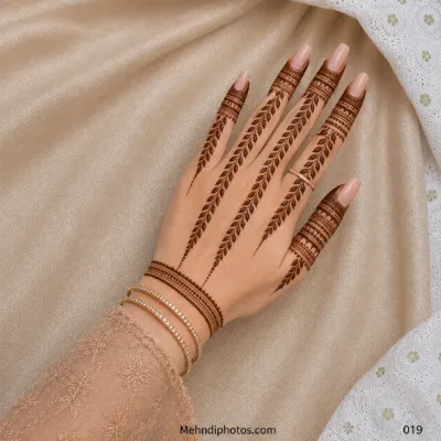 Back hand with long leafy mehndi vines, detailed ornamental finger bands, dotted trails and a bracelet-style wrist border.
