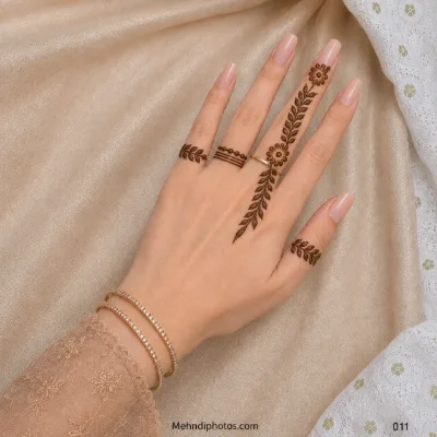 Back hand with a floral leafy vine extending from the ring finger, small leaf bands and minimal ring-style mehndi details.