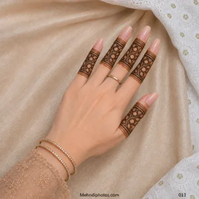 Back hand with bold ornamental mehndi panels featuring curved leaves, circular details and horizontal bands on every finger.