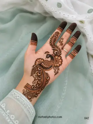 Explore a royal front hand mehndi design with an intricate peacock, floral details and feather motifs, perfect for weddings and festive occasions.